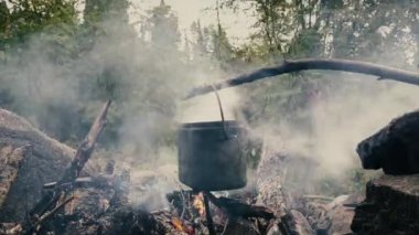 Turist şapkası dağlardaki ateşin üstünde asılı.