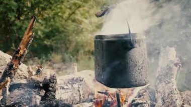Turist şapkası dağlardaki ateşin üstünde asılı.