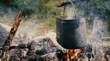 Turist şapkası dağlardaki ateşin üstünde asılı.