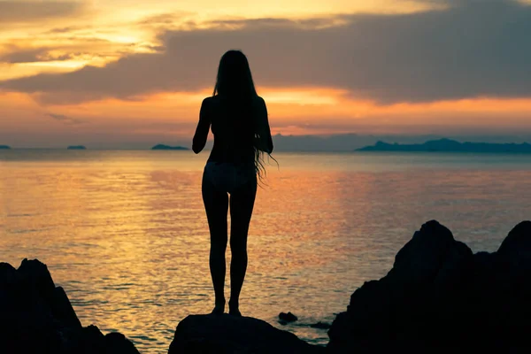 一位留着长发 站在海边欣赏着艳阳高照的年轻女子的侧影 — 图库照片