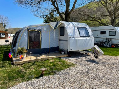 Karavan kamp alanındaki bir seyahat karavanının önünde açık bir çadır. Karavan kamp konsepti. 