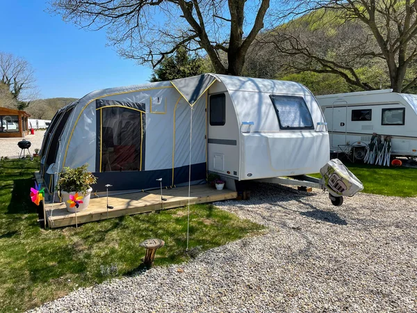 An open tent in front of a travel trailer at a caravan campsite. Caravan camping concept.