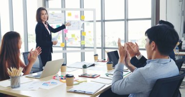 Mutlu iş adamları toplantı odasında grafik çizelgesi yatırımıyla ve iş verileriyle tanışıyor. Bir grup iş adamı konferans odasında toplanıyor. Asyalı iş adamı konuşması, mevcut takım çalışması ortaklığı