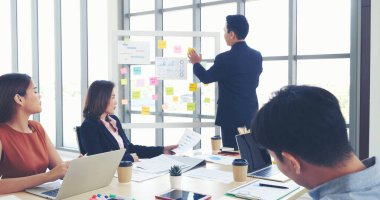 Bir grup iş adamı konferans odasında toplanıyor. Asyalı iş adamı konuşması, mevcut takım çalışması ortaklığı. Mutlu iş adamları toplantı odasında grafik çizelgesi yatırımı ve iş verilerini karşılıyorlar.