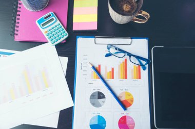 Ofis dizüstü bilgisayarının finansal döküman şeması ve kahve fincanı ile ahşap masanın üzerindeki grafiği. Düz dizüstü bilgisayar ofis masasında duruyordu. İş sahasında iş grafiği modellemesi yok