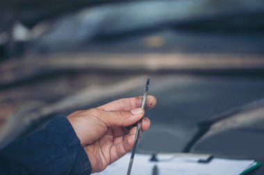Araba tamircisi, servis alanında motor yağı mekaniğini elle kontrol ediyor. El kapatma adam motor yağı seviyesini kontrol et. Dipstick 'i bul, temizle, motor yağı doldurmadan önce dipstick seviyesini kontrol et.