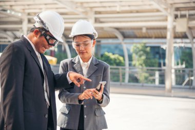 İnşaat mühendisi takımları modern kentteki inşaat sahasında birlikte çalışan işçi kaskı takıyorlar. Foreman Endüstri Mühendislik Mühendisliği ekip çalışması. Asya endüstrisi profesyonel takımı