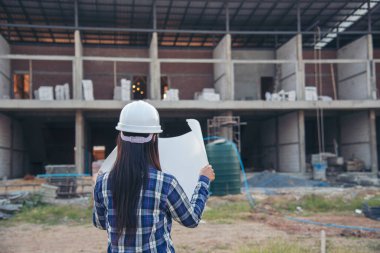 İnşaat mühendisi kadın işçi sanayisinde ekose gömlekli, beyaz kasketli, inşaat işçisi. Mimari mühendis kadın memur emlak projesine bakıyor.