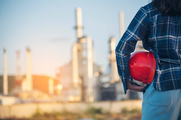 Woman Emergency workers hands holding hardhat red work helmet Engineer. Refinery plant woman worker oil petrochemical industry hand holding red worker hard hat. Refinery industry engineer manufacture