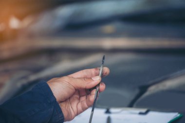 Araba tamircisi, servis alanında motor yağı mekaniğini elle kontrol ediyor. El kapatma adam motor yağı seviyesini kontrol et. Dipstick 'i bul, temizle, motor yağı doldurmadan önce dipstick seviyesini kontrol et.