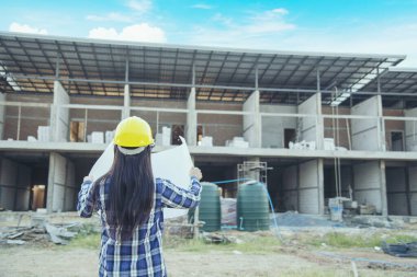 İnşaat mühendisi kadın işçi sanayisinde ekose gömlekli, beyaz kasketli, inşaat işçisi. Mimari mühendis kadın memur emlak projesine bakıyor.