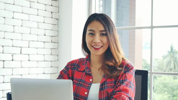 Happiness Asian Woman working from home using laptop online meeting in home office. Happy relax time asian business woman typing keyboard use notebook laptop Smiling, laughing, yawn at home office.