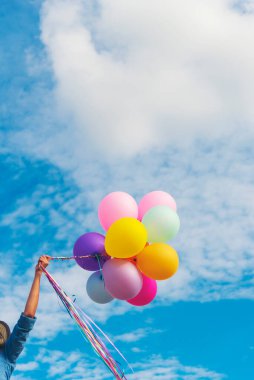 Yeşil çayır bulutu üzerinde koşan balonları tutan bir kadın. Mavi gökyüzü. Mutluluk dolu ve rahatlatıcı. Hava balonları tutan eller doğum günü partisinde oynar Mutlu zamanlar yaz güneşi açık havada