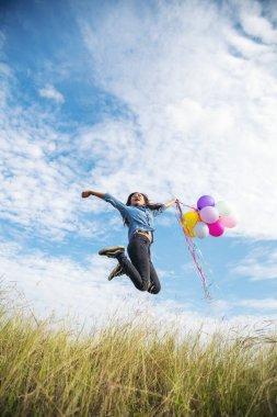 Yeşil çayır üzerinde koşan balonlar tutan neşeli şirin kız beyaz bulut ve mutlulukla mavi gökyüzü. Hava balonları tutan eller doğum günü partisinde oynar. Mutlu zamanlar yaz mevsimi açık havada.