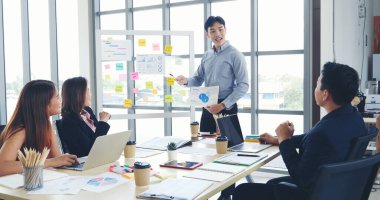 Bir grup iş adamı konferans odasında toplanıyor. Asyalı iş adamı konuşması, mevcut takım çalışması ortaklığı. Mutlu iş adamları toplantı odasında grafik çizelgesi yatırımı ve iş verilerini karşılıyorlar.