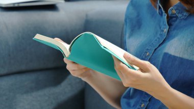 Oturma odasında kitap okuyan Asyalı kadın kitap okuyacak. Genç kadın gevşeme okuyucusu açık kitap boş zihin okuyor. Mutluluk, güzel kadın, gülen surat, mutlu zaman.