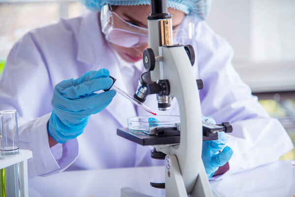 Closeup Woman scientist hand use dropper in lab look at science microscope medical test, research biology chemistry. Females technician laboratory analyzing blood scientific pharmaceutical research.