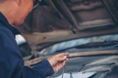 Araba tamircisi, servis alanında motor yağı mekaniğini elle kontrol ediyor. El kapatma adam motor yağı seviyesini kontrol et. Dipstick 'i bul, temizle, motor yağı doldurmadan önce dipstick seviyesini kontrol et.