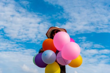 Yeşil çayır bulutu üzerinde koşan balonları tutan bir kadın. Mavi gökyüzü. Mutluluk dolu ve rahatlatıcı. Hava balonları tutan eller doğum günü partisinde oynar Mutlu zamanlar yaz güneşi açık havada