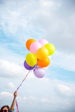 Yeşil çayır bulutu üzerinde koşan balonları tutan bir kadın. Mavi gökyüzü. Mutluluk dolu ve rahatlatıcı. Hava balonları tutan eller doğum günü partisinde oynar Mutlu zamanlar yaz güneşi açık havada