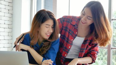 Ofis masasında kendine güvenen iki kadının birlikte çalışması mutluluktur. Bilgisayar şirketi ile çalışan takım ortakları. Asyalı iş arkadaşı arkadaşlığı gülen yüzle iş başında.