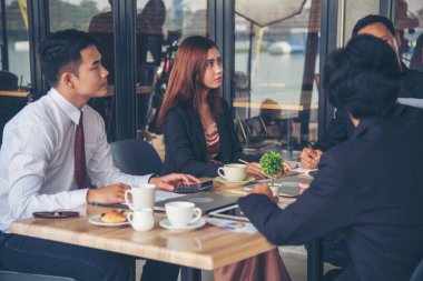 Bir grup iş adamı konferans odasında toplantı yapıyor. İşletme doküman grafiği ofis masasına danışmak için beyin fırtınası yapıyorlar. Çeşitli etnik gruplardan iş adamları beyin fırtınası yapıyor ve birlikte çalışıyorlar..
