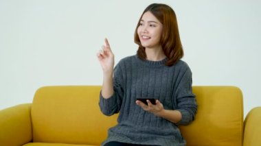 Gülümseyen Asyalı kadın elinde e-ticaret alışverişi internet sitesi Reading Online Article, Blog, vlog ile akıllı telefon tutuyor. Genç kadının elleri telefon teknolojisi yaşam tarzını tutuyor. Akıllı telefon kullanan kadın.