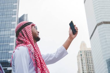 Akıllı telefon uygulaması kullanan İslami adam, ajandasını akıllı telefon Müslüman modern uae şehrine odaklıyor. Arap erkekleri tesettür ve Müslüman resmi giysileri giyer. Çevrimiçi yaşam tarzı mesajları gönderir.