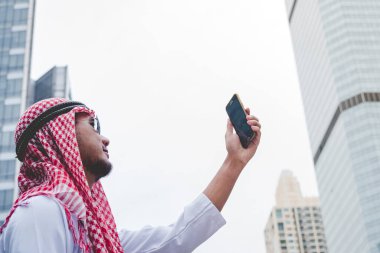 Akıllı telefon uygulaması kullanan İslami adam, ajandasını akıllı telefon Müslüman modern uae şehrine odaklıyor. Arap erkekleri tesettür ve Müslüman resmi giysileri giyer. Çevrimiçi yaşam tarzı mesajları gönderir.