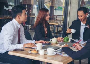 Bir grup iş adamı konferans odasında toplantı yapıyor. İşletme doküman grafiği ofis masasına danışmak için beyin fırtınası yapıyorlar. Çeşitli etnik gruplardan iş adamları beyin fırtınası yapıyor ve birlikte çalışıyorlar..