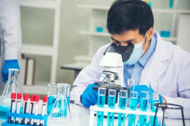 Bilim adamı bilim laboratuarındaki mikroskop araştırmalarını inceliyor. Asyalı bilim adamı laboratuvar kimya laboratuvarlarını arıyor. Covid-19 Coronavirus biyokimya araştırma deneyi aşı konsepti