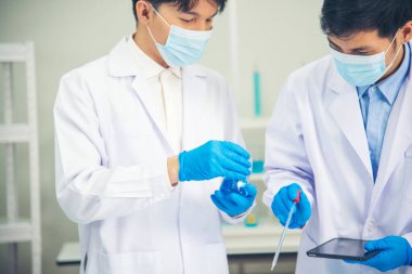 İki Asyalı bilim adamı kimya bilimi tüpü deney tüpü antikor örneğini kovid-19 virüsüne karşı laboratuvar geliştirmek için depoluyorlar. Kimya Laboratuarı 'nda bilim adamı danışmanı, analizi