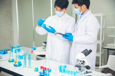 İki Asyalı bilim adamı kimya bilimi tüpü deney tüpü antikor örneğini kovid-19 virüsüne karşı laboratuvar geliştirmek için depoluyorlar. Kimya Laboratuarı 'nda bilim adamı danışmanı, analizi