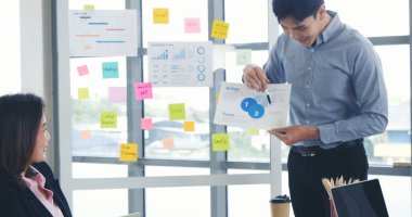 Mutlu iş adamları toplantı odasında grafik çizelgesi yatırımıyla ve iş verileriyle tanışıyor. Bir grup iş adamı konferans odasında toplanıyor. Asyalı iş adamı konuşması, mevcut takım çalışması ortaklığı