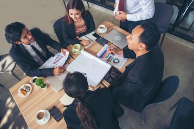 Bir grup iş adamı konferans odasında toplantı yapıyor. İşletme doküman grafiği ofis masasına danışmak için beyin fırtınası yapıyorlar. Çeşitli etnik gruplardan iş adamları beyin fırtınası yapıyor ve birlikte çalışıyorlar..