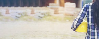 İnşaat alanında inşaat mühendisi kadın elleri beyaz kasklı işçi kaskı tutuyor. Panorama Endüstri Mühendisi kadın işçi miğferini tutuyor. Kopyalama alanı ile ağ arkaplanı