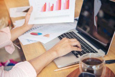 Akıllı telefon kullanan bir iş kadını, ofis masasında dizüstü bilgisayar. Finansal grafik grafikleri okuyan serbest çalışan bir kadın pazarlama verilerini analiz etmeyi planlıyor. Şirkette çalışan genç bir kadının elleri..