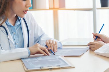 İki Asyalı kadın doktor dizüstü bilgisayarlı hasta danışmanlığı kullanarak doktorun muayenehanesiyle görüşmeyi tartışıyor. Asya tıp laboratuarındaki genç kadınlar birlikte sağlık hizmetleri ekip çalışmasını tartışıyorlar.