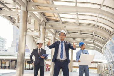 İnşaat mühendisi takımları modern kentteki inşaat sahasında birlikte çalışan işçi kaskı takıyorlar. Foreman Endüstri Mühendislik Mühendisliği ekip çalışması. Asya endüstrisi profesyonel takımı