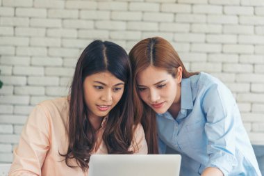 Ofis masasında kendine güvenen iki kadının birlikte çalışması mutluluktur. Bilgisayar şirketi ile çalışan takım ortakları. Asyalı iş arkadaşı arkadaşlığı gülen yüzle iş başında.