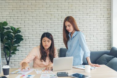 Asyalı iş arkadaşı arkadaşlığı, gülen yüzle. Mutluluk iki kadın meslektaşın ofis masasında takım çalışması. Bilgisayar şirketi ile çalışan takım ortakları