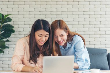 Asyalı iş arkadaşı arkadaşlığı, gülen yüzle. Mutluluk iki kadın meslektaşın ofis masasında takım çalışması. Bilgisayar şirketi ile çalışan takım ortakları