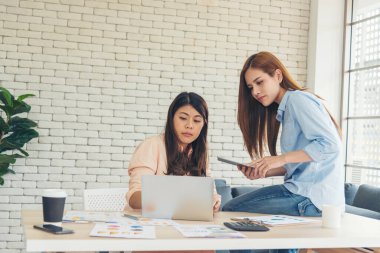 Ofis masasında kendine güvenen iki kadının birlikte çalışması mutluluktur. Bilgisayar şirketi ile çalışan takım ortakları. Asyalı iş arkadaşı arkadaşlığı gülen yüzle iş başında.