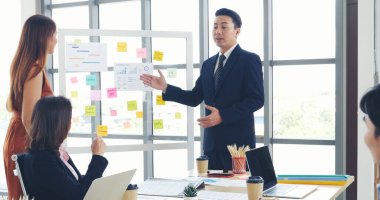 Mutlu iş adamları toplantı odasında grafik çizelgesi yatırımıyla ve iş verileriyle tanışıyor. Bir grup iş adamı konferans odasında toplanıyor. Asyalı iş adamı konuşması, mevcut takım çalışması ortaklığı