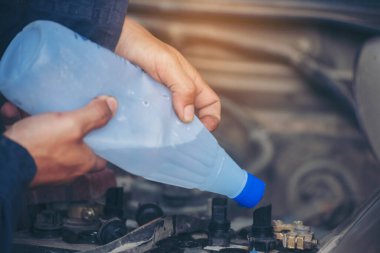 Araba tamircisi elleri araba aküsü mekanik servisi için arıtılmış arıtılmış su döküyor. Kapatın elleri adamım. Deiyonize edilmiş sıvı su şişesini garajdaki mobil araba servisinde tutun.