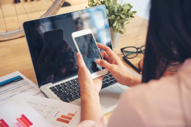 Akıllı telefon kullanan bir iş kadını, ofis masasında dizüstü bilgisayar. Finansal grafik grafikleri okuyan serbest çalışan bir kadın pazarlama verilerini analiz etmeyi planlıyor. Şirkette çalışan genç bir kadının elleri..