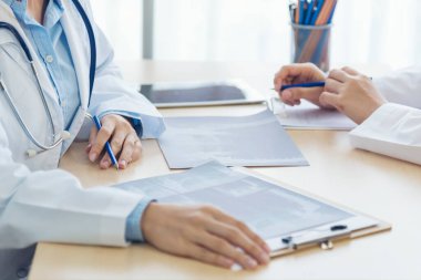 Sağlık hizmetleri ekip çalışmasını tartışan iki doktor kadının ellerini kapatın. İki Asyalı kadın el doktorları buluşması reçeteli sağlık kliniği yazıyorlar. Doktor laptop yazma notu kullanarak tartışır