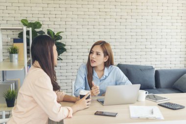 İki iş kadını takım toplantısı şirket masasında dizüstü bilgisayarla yapılıyor. Finansal grafik grafikleri okuyan iki genç kadın pazarlama verilerini analiz etmeyi planlıyor. Asyalı ekip çalışma bürosu.