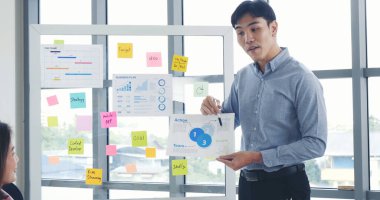 Bir grup iş adamı konferans odasında toplanıyor. Asyalı iş adamı konuşması, mevcut takım çalışması ortaklığı. Mutlu iş adamları toplantı odasında grafik çizelgesi yatırımı ve iş verilerini karşılıyorlar.