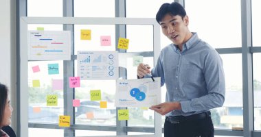 Mutlu iş adamları toplantı odasında grafik çizelgesi yatırımıyla ve iş verileriyle tanışıyor. Bir grup iş adamı konferans odasında toplanıyor. Asyalı iş adamı konuşması, mevcut takım çalışması ortaklığı